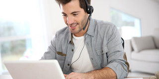 Mann in Videokonferenz Mann sitzt vor dem Laptop und hat ein Headset auf.