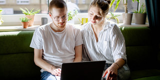 Studierende arbeiten digital Zwei Studierende arbeiten am Laptop, auf einem Sofa sitzend.