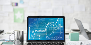 Laptop auf Tisch Ein Laptop mit mathematischen Formeln steht auf einem weißen Schreibtisch neben einer Tasse, Stiften und Blättern.