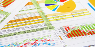 Diagramme_01 Papierseiten mit Tabellen, Kreis-, Säulen- sowie Graphdiagrammen liegen übereinander.